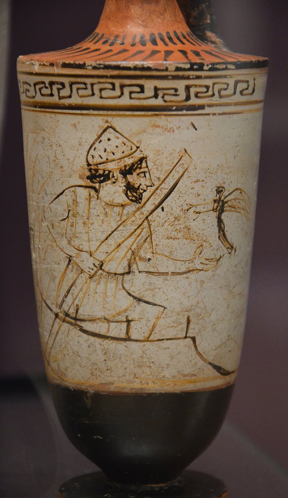 Athenian white-ground oil flask made for a grave, about 460 to 450 BC, by the Tymbos Painter. No ancient image of Melinoe survives. The hymn says she sends airy phantoms in the night; Greek painters drew a dead person's soul as a tiny winged figure, like this one flying to Charon, the ferryman of the dead.