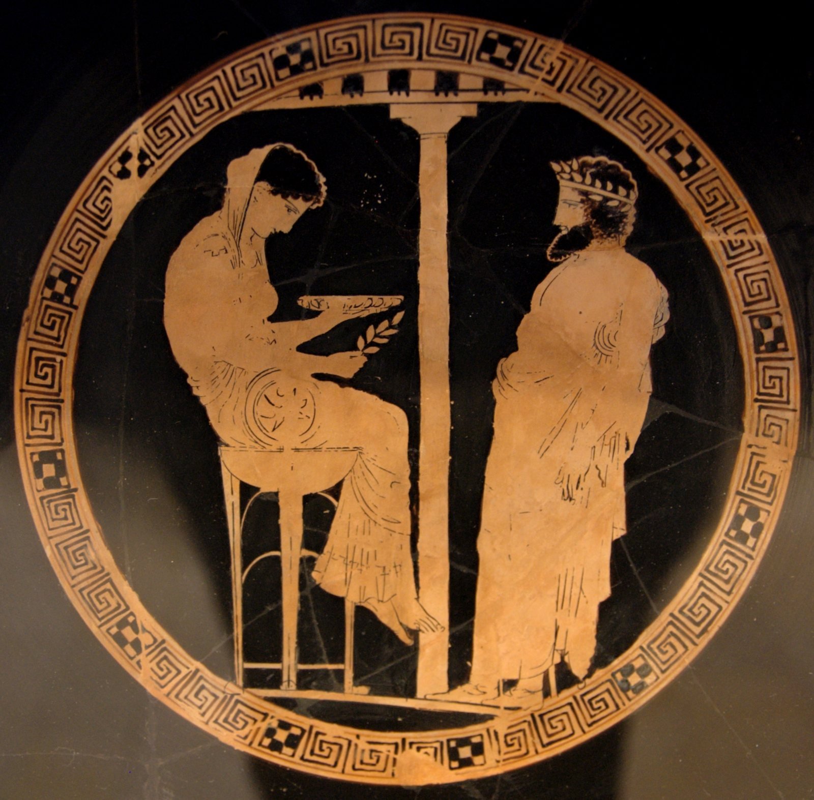 Athenian red-figure cup, 440 to 430 BC, by the Kodros Painter. Themis, named beside her, sits on the tripod at Delphi with a bowl and a laurel sprig and gives an oracle to King Aegeus of Athens.