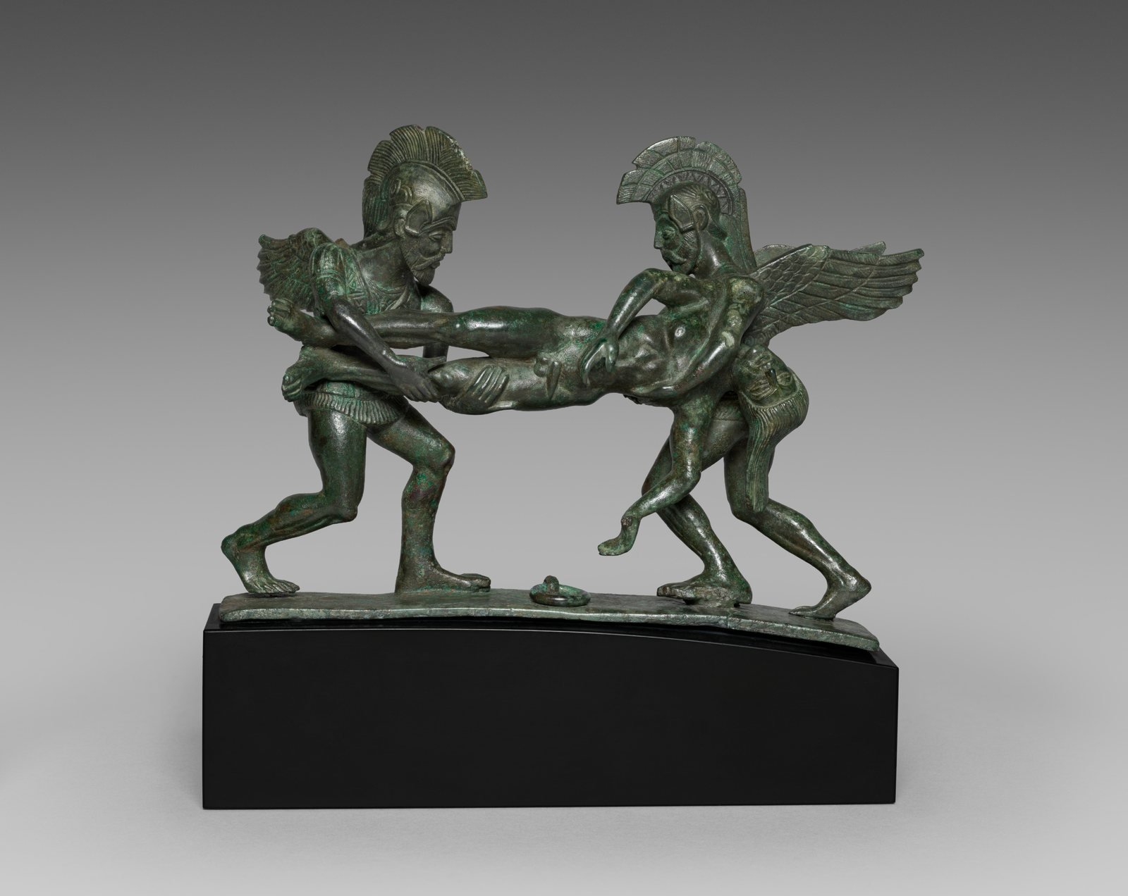 Etruscan bronze handle from the lid of a cista, a round box, 400 to 375 BC. Two winged gods, probably Sleep and Death, carry off a dead warrior, perhaps Sarpedon, son of Zeus, whose body they took home to Lycia in Homer's Iliad.